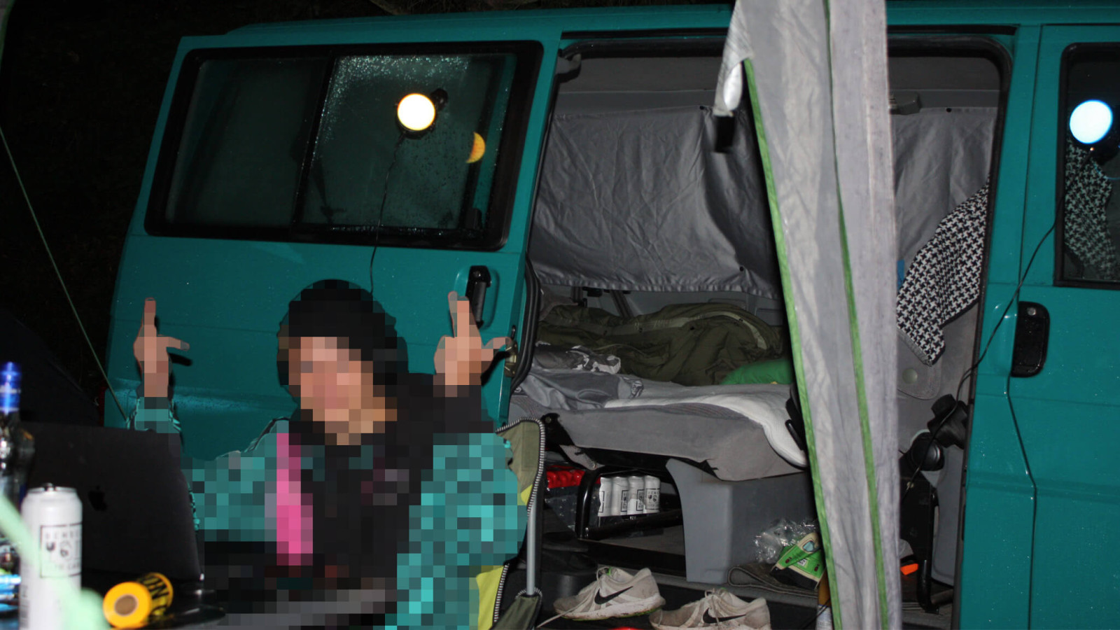 Offener VW Bus mit Schlafplatz auf dem Campingplatz am Nürburgring, Freund legt Musik auf Laptop