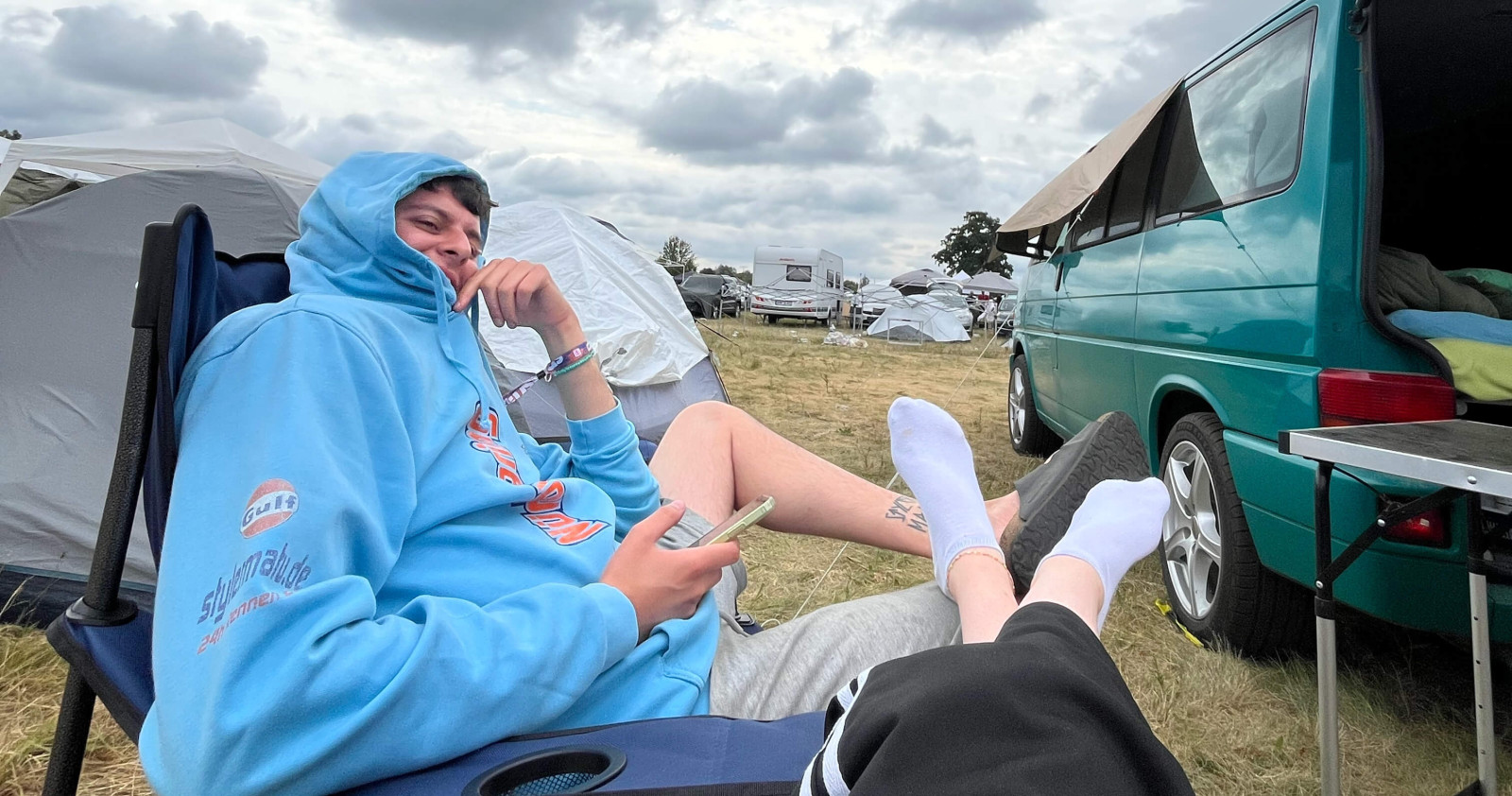 Relaxte Szene beim splash! Festival Campingplatz mit VW Bus, stylermatu auf Campingstuhl